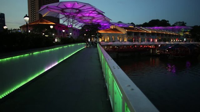 Clarke Quay bridge and Riverside area at evening in Singapore, Southeast Asia. Waterfront skyline reflected on Singapore River. Popular attraction for nightlife.