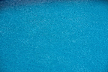 Water with small waves and raindrops on a pool with blue texture background