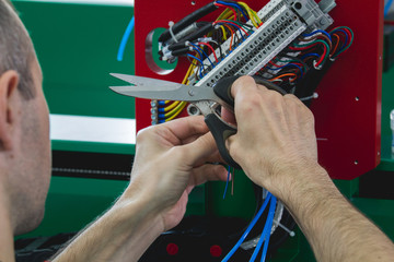 Electrician works with parts of energy equipment on plant