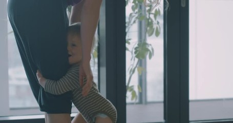 Young mother playing with toddler on yoga mat