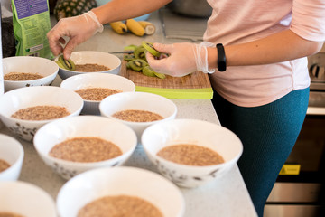 indoor portrait of young caucasian girl cooking healthy food breakfast with porridge and fruits