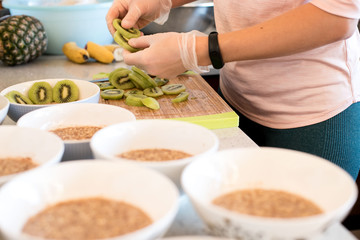 indoor portrait of young caucasian girl cooking healthy food breakfast with porridge and fruits