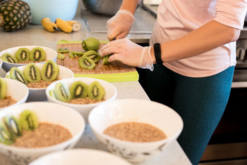 indoor portrait of young caucasian girl cooking healthy food breakfast with porridge and fruits