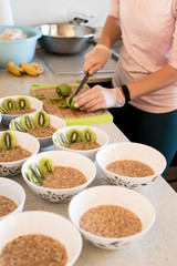 indoor portrait of young caucasian girl cooking healthy food breakfast with porridge and fruits