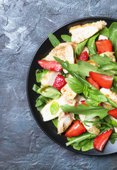 Delicious salad with arugula, strawberries and grilled chicken, top view
