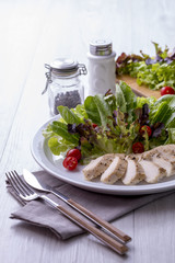Chicken breast salad on a white plate with fork and knife