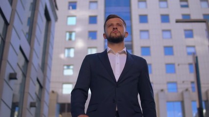 young professional businessman walking in city downtown background. successful young caucasian man wearing elegant blue jacket and white shirt going down the street