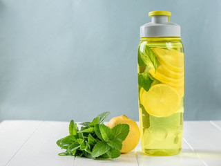 Sports bottle with mint and lemon drink on white wooden table.Bottle for sports.