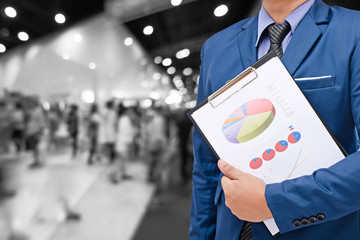 businessman and graph report on blurred event with people background