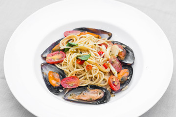 Pasta spaghetti with mussel and tomatoes isolated on white plate
