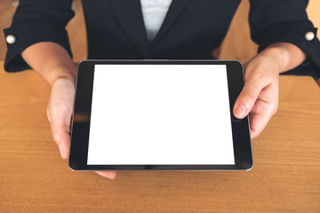 Mockup image of businesswoman holding and showing a black tablet pc with blank white desktop screen on table
