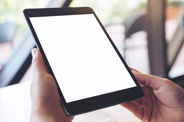 Mockup image of hands holding and using a black tablet pc with blank white desktop screen