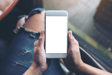 Top view mockup image of woman's hands holding white mobile phone with blank screen
