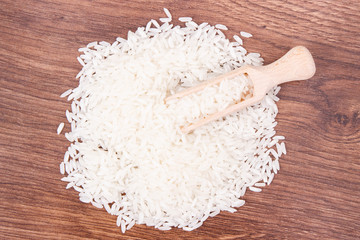 White rice and wooden scoop on rustic board