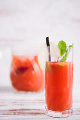 Watermelon and strawberries fruit juice on glass with mint leaves on a white board,