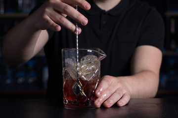 Bartender stirring alcoholic cocktail in a measuring glass.