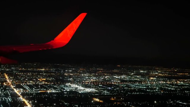 Bangkok, Thailand- Jun 4, 2018. Thai Airasia airline flight FD 3010 fly from Phuket (HKT) to Donmuang Bangkok (DMK) is landing. View from window seat Illuminated city in dark night. 