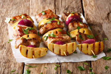 Freshly prepared pork skewers with apples and red onions close-up on parchment. horizontal