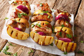 Tasty skewers of pork with fresh apples and red onions close-up on paper. horizontal