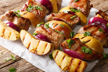 Spicy pork kebabs with apples and red onions close-up on the table. horizontal, rustic