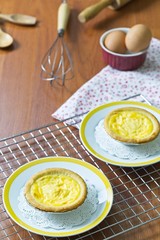 Dessert egg tart sweet custard pie on white plate, portuguese egg tart in oven tray on wooden background with copy space