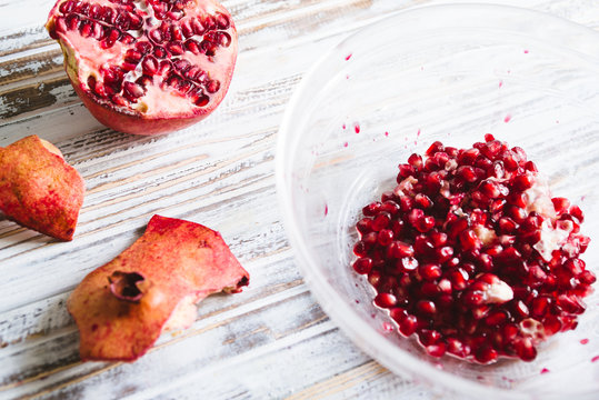 Pomegranate seeds on a glass bowl,on a white wooden board against a blue background