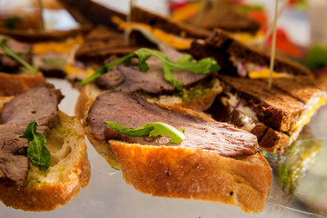 sandwiches with meat and pesto sauce on a banquet table