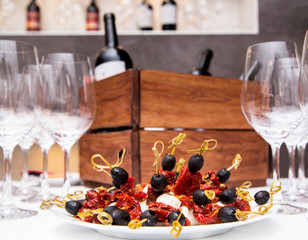 a bottle of wine in a wooden box and a snack on skewers