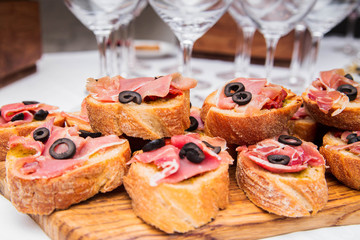Snacks with ham on the banquet table and glasses of wine