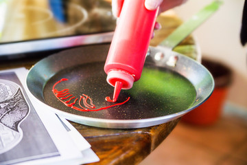 Fototapeta na wymiar the cook draws a strawberry sauce in a frying pan