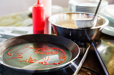 the cook draws a strawberry sauce in a frying pan