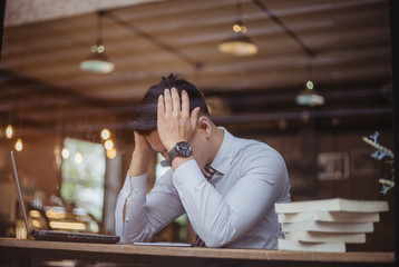Sad businessman sitting at the table with many folders in office