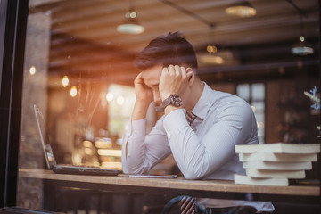 Sad businessman sitting at the table with many folders in office