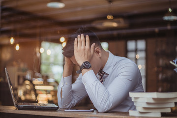 Sad businessman sitting at the table with many folders in office