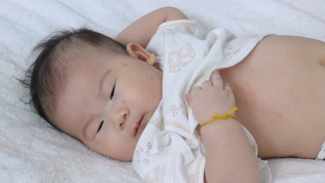 Newborn baby lying on the bed and looking at camera. Healthy children concept.
