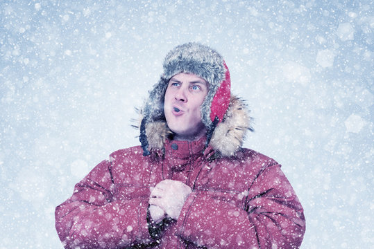 Frozen man in red winter clothes lets the steam out of his mouth, cold, snow, blizzard 