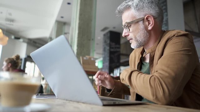 Man in trendy coffee shop working on laptop computer