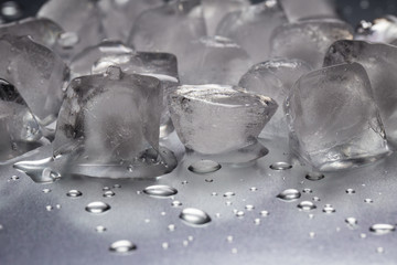 Ice cubes on a reflecting table with drops of water close-up