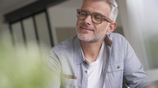 Middle-aged guy with trendy eyeglasses relaxing at home