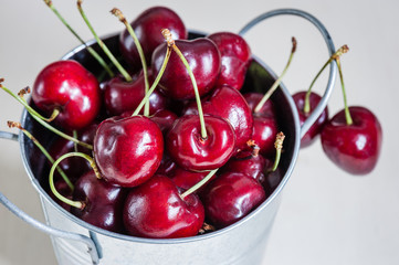 Close-up of little bucket with fresh and juicy cherries on a light background. Top view.