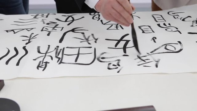 Chinese girl drawing chinese ieroglifs, national art, writing and drawing of bunch of sakura flowers