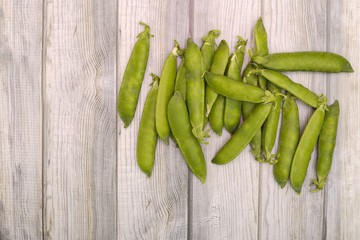 Green pea pods on a wooden background