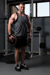 Obraz na płótnie Canvas Bodybuilder Holding Weights In Hand