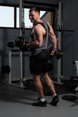 Fototapeta na wymiar Bodybuilder Exercising Biceps With Dumbbells