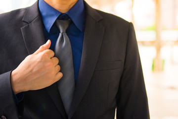 Asian business man is touching one side of his black formal suit for talent concept in working.