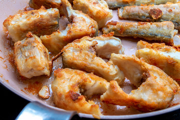 Pieces of fish fried in a hot pan