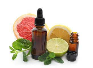 Bottles of citrus essential oil and fruits on white background