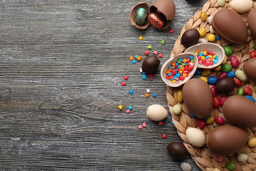 Chocolate Easter eggs, colorful sprinkles and candies on wooden background