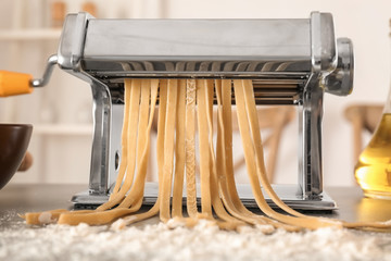 Metal pasta maker with dough on kitchen table