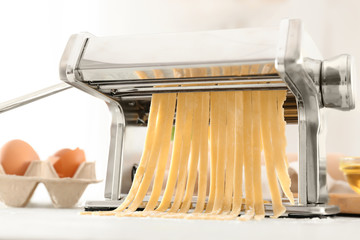 Obraz na płótnie Canvas Metal pasta maker with dough on kitchen table